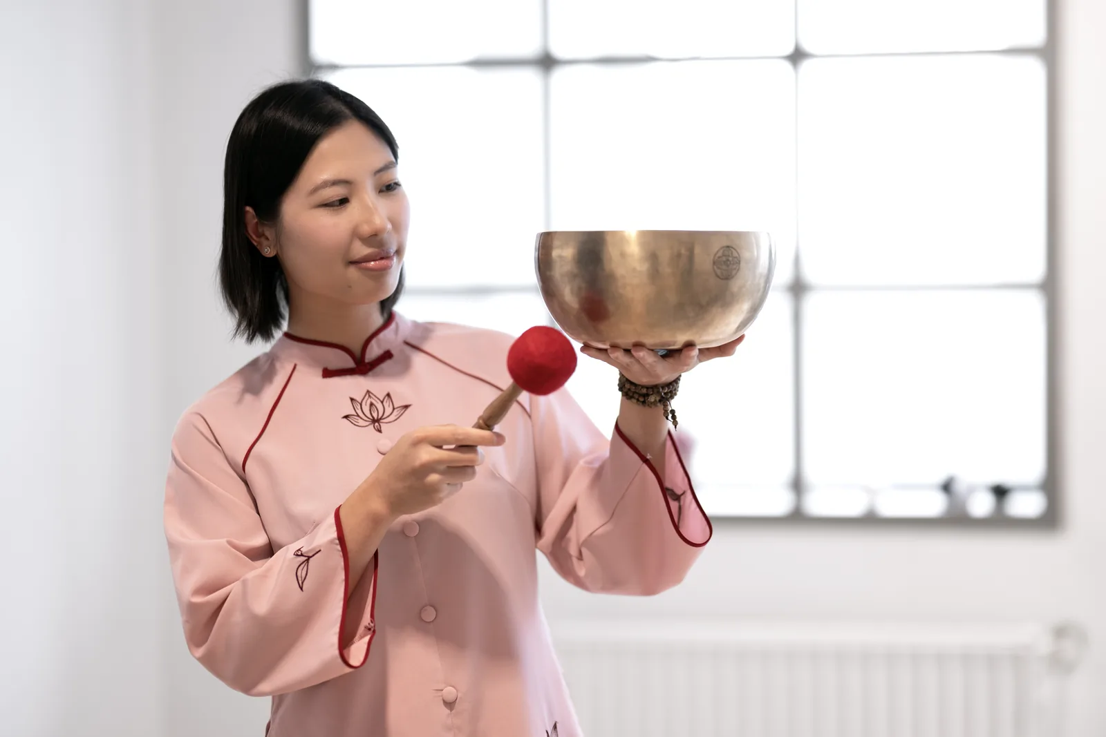 Phuong hält eine Klangschale und schlägt sie mit einem Klöppel an