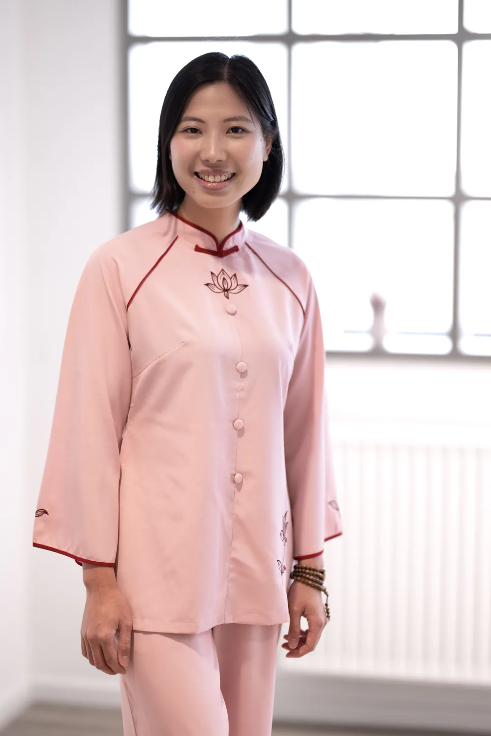 Phuong in rosafarbener Kleidung mit gesticktem Lotus